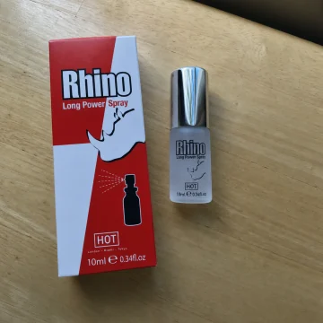 Die Verpackung des Rhino Long Power Spray und die 10-ml-Flasche auf einem Holztisch